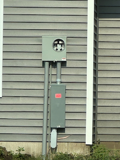 Photo of separate Meter Socket and Breaker on the side of a building 